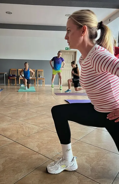 Uczestniczki warsztatu wykonują przysiad w sali